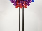 une grande lampe multicolore posée sur un pied métallique avec une base noire