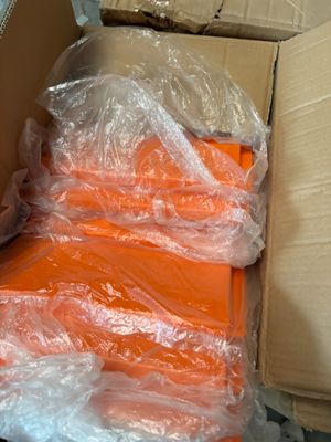 many bags of orange shirts in a box on the floor