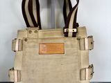 beige canvas and leather tote bag on stand on black surface
