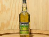 une bouteille de Chartreuse posée sur un tonneau en bois