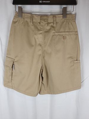 un gros plan sur un short beige suspendu à un cintre, sur fond blanc
