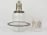 a small glass bottle with a gold lid next to a shot glass