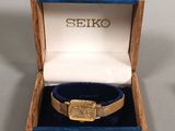 a gold watch in a blue box with a gold band