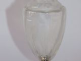 un vase en verre transparent avec un couvercle en argent, posé sur une table