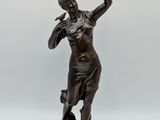 bronze statue of a woman holding a bird on a pedestal