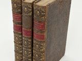 three old books sitting on top of each other on a white surface