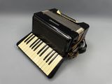a black accordion sitting on top of a table next to a keyboard