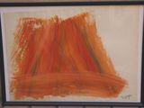 painting of orange and brown brush strokes in a black frame on a brick wall
