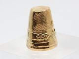 a gold thimble sitting on a white surface