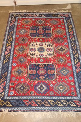 a red and blue rug sitting on top of a cement floor