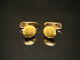 deux paires de boutons de manchette en or sur un fond noir