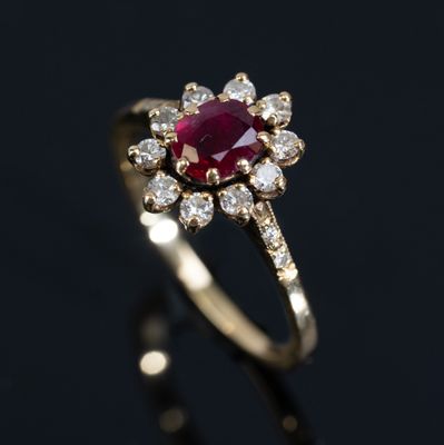 a close up of a gold ring with a ruby and diamonds