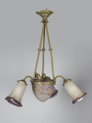 un lustre ancien en laiton, muni de trois abat-jours en verre, suspendu au plafond