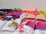 many pairs of slippers on a table with a price tag
