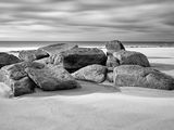 black and white photograph of rocks on a beach with a cloudy sky