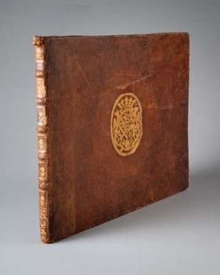 un vieux livre marron orné d'un emblème doré sur la couverture