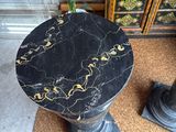 a black marble table with a plant on top