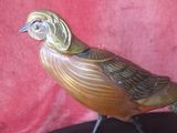 un oiseau en bronze posé sur un socle noir