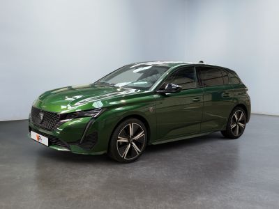 Une voiture verte est garée dans une pièce aux murs blancs.