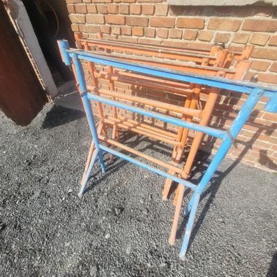 a blue and orange metal rack sitting in front of a brick wall