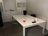 une table blanche sur laquelle se trouve une tasse rouge, dans une pièce