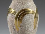 a white vase with a gold decoration on it