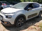 une Citroën blanche garée dans un champ, avec d'autres voitures en arrière-plan