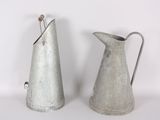 two metal pitchers sitting next to each other on a table