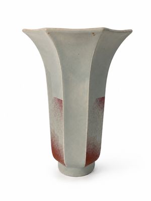 un vase blanc et rouge posé sur une surface blanche