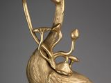 gold sculpture of a bird with a long neck and a long beak