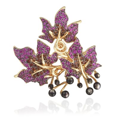 a close up of a brooch with purple stones and pearls