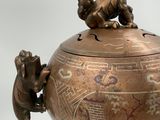 a bronze teapot with two animals on top of it