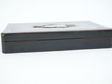 a black box with a silver lid sitting on a white surface