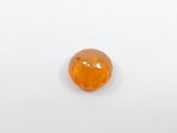 a close up of an orange gemstone on a white surface