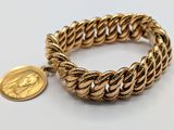 a close up of a gold bracelet with a coin on it