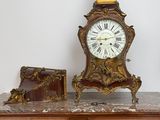 a clock sitting on top of a dresser next to a suitcase
