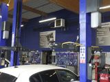 une voiture blanche garée dans un garage équipé d'un pont élévateur bleu