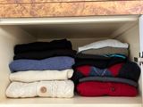 a lot of sweaters that are stacked up in a cabinet