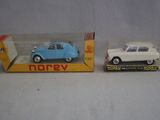 Deux petites voitures sont posées dans une boîte sur une table.