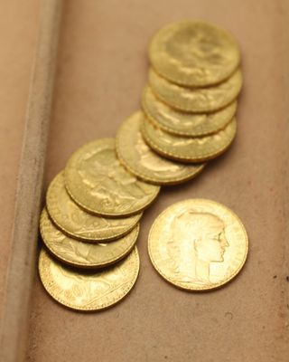 un tas de pièces d'or posées sur une table, à côté d'un penny