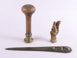 deux morceaux de métal et un manche en bois posés sur une surface blanche