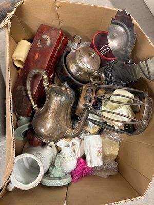 une boîte en carton posée par terre et remplie d'objets divers