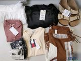 Plusieurs paires de chaussures et plusieurs vêtements sont disposés sur une table
