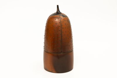 a brown vase with a black top on a white surface