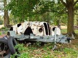 a rusted out old car sitting in the grass