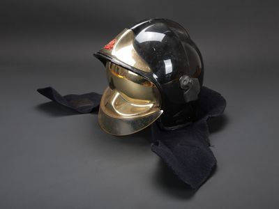 un casque noir et doré posé sur une écharpe noire, sur fond gris