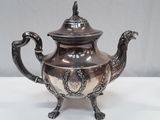 a silver tea pot on a stand on a white table