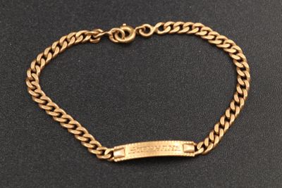 gros plan d'un bracelet en or sur une surface noire