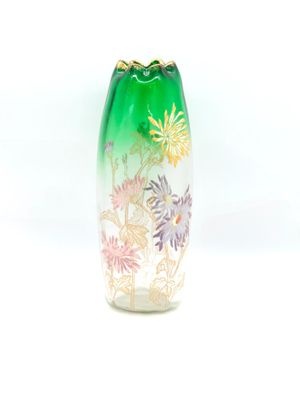 a green vase with flowers on it on a white surface