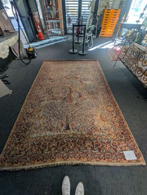 un tapis posé à même le sol dans un magasin, avec une paire de chaussures à côté